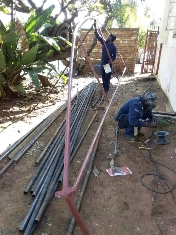 Workers fabricating greenhouse steel frames